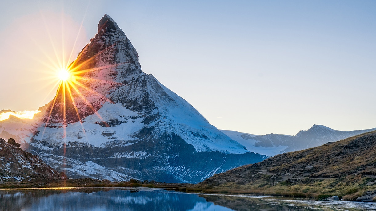 Sunrise over the Matterhorn at Glacier Paradise, Switzerland, reflecting in a tranquil lake.