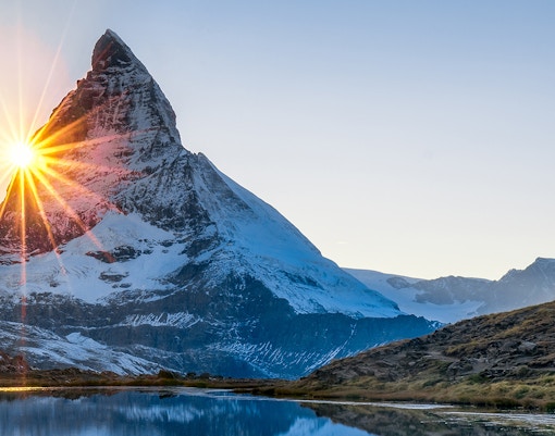 Sunrise over the Matterhorn at Glacier Paradise, Switzerland, reflecting in a tranquil lake.