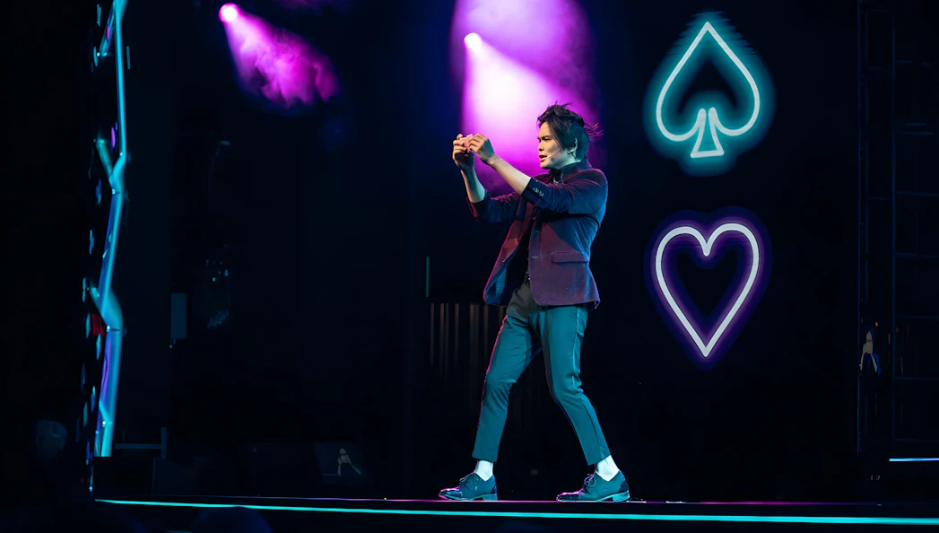 Magician performing card trick on stage at Shim Lim show, Las Vegas.