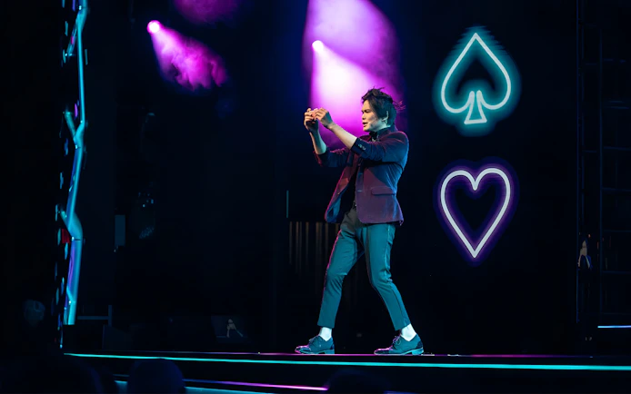 Magician performing card trick on stage at Shim Lim show, Las Vegas.