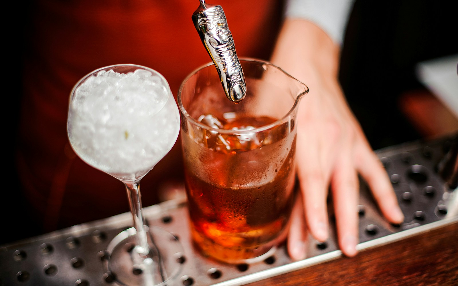 Cocktail with ice and spooky finger stirrer on bar counter.