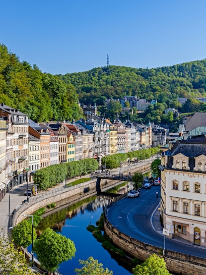 Row of colorful historic buildings along the river in the old quarter of Karlovy Vary.