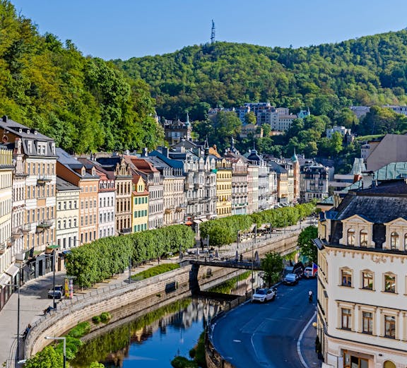 Row of colorful historic buildings along the river in the old quarter of Karlovy Vary.