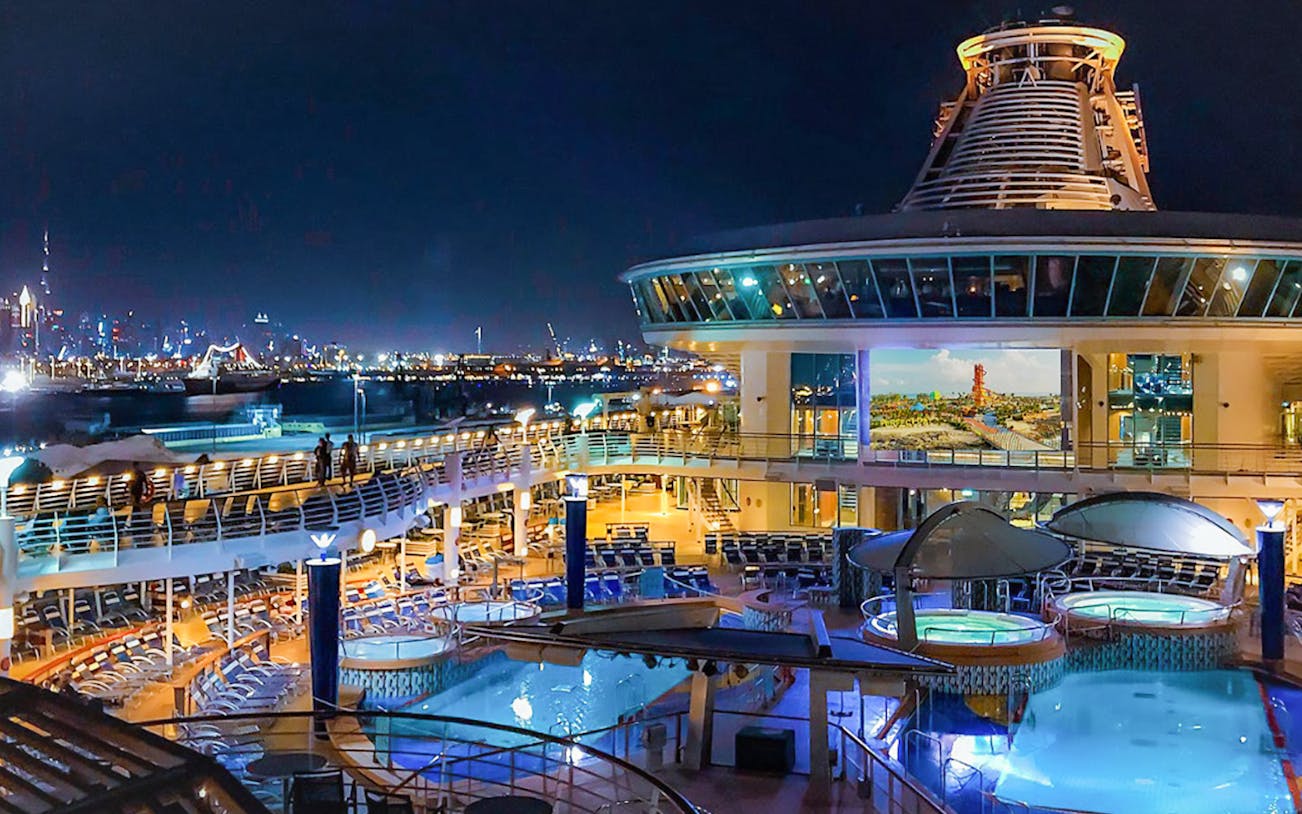 Cruise ship deck at night with pool and city skyline, Malaysia and Thailand Getaway.