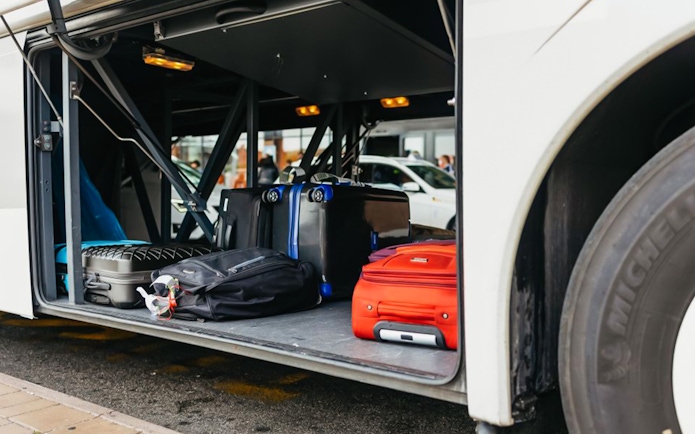 Luggage stored in the compartment of an airport transfer bus.