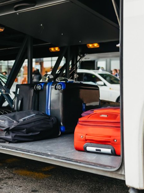 Luggage stored in the compartment of an airport transfer bus.