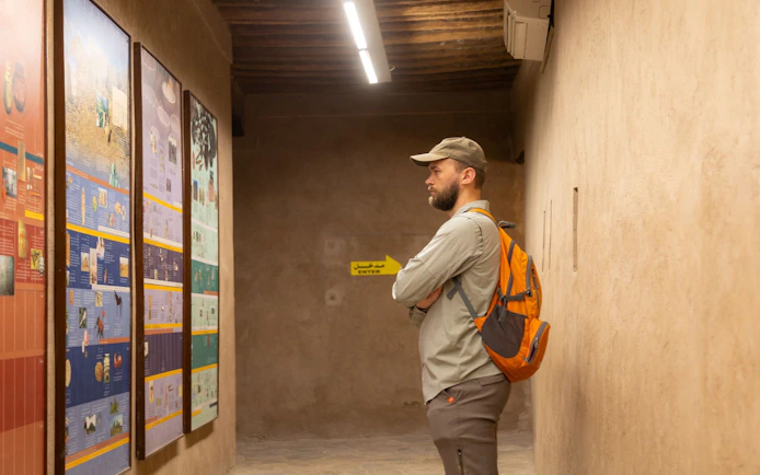 Tourist reading informational panels inside Nizwa Fort, Oman.