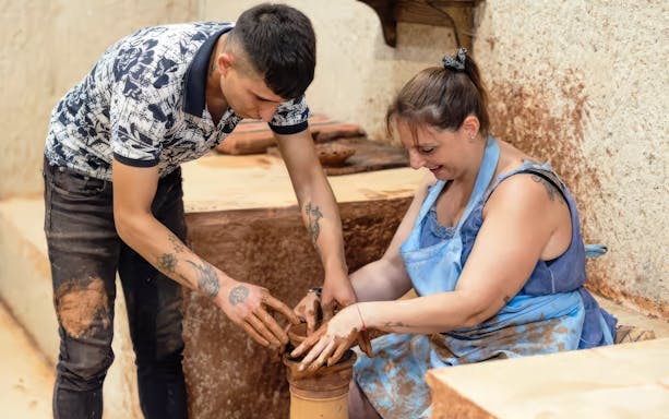 Pottery workshop in Avanos with participants shaping clay on a wheel.