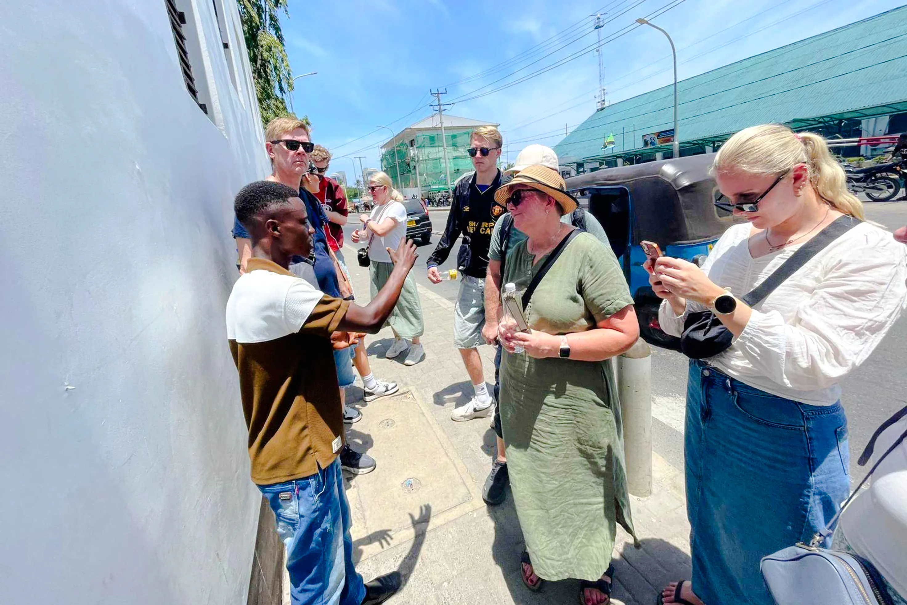 Tour guide explaining history to a group during Dar es Salaam walking tour, Zanzibar.