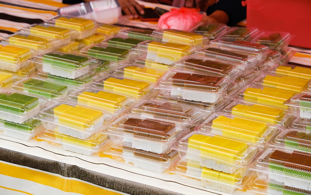 Assorted traditional Indonesian snacks in plastic containers at a Batam market stall.
