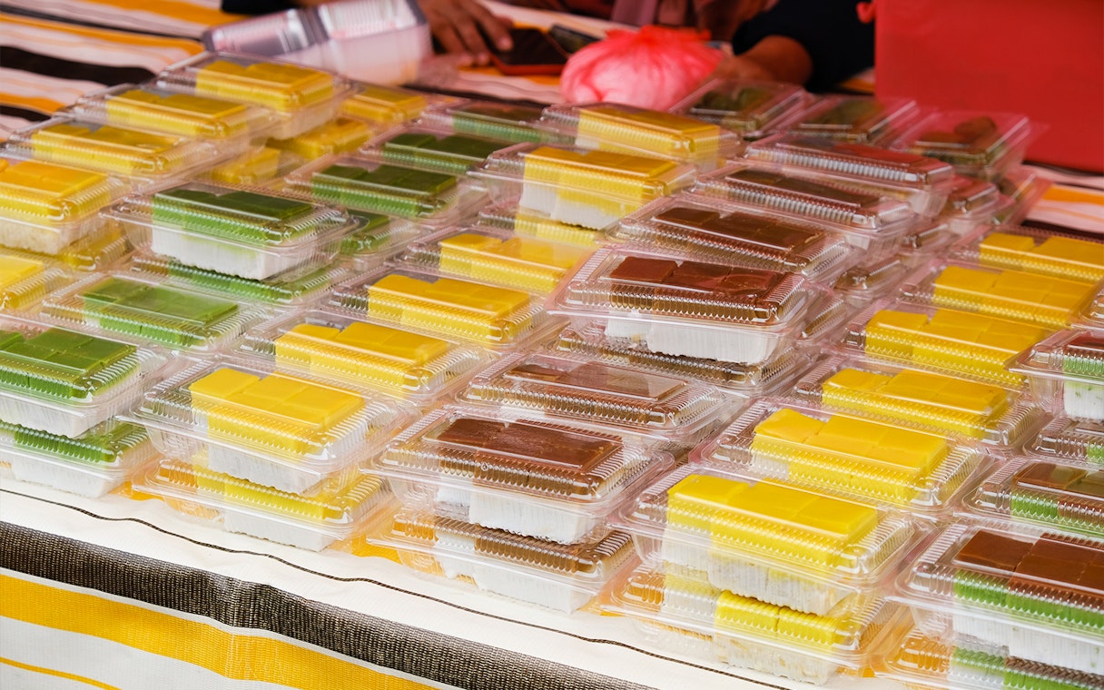 Assorted traditional Indonesian snacks in plastic containers at a Batam market stall.