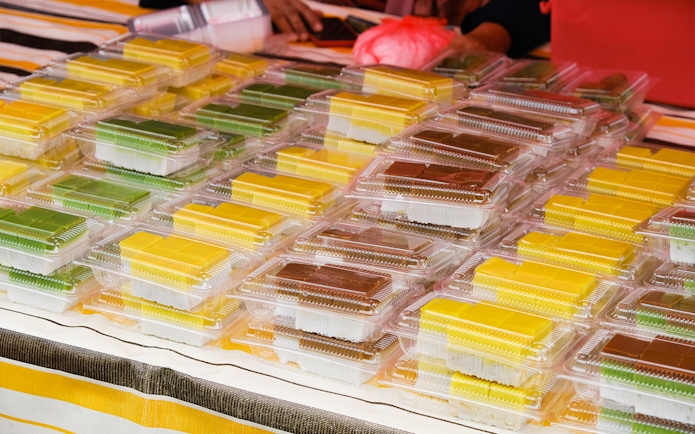 Assorted traditional Indonesian snacks in plastic containers at a Batam market stall.