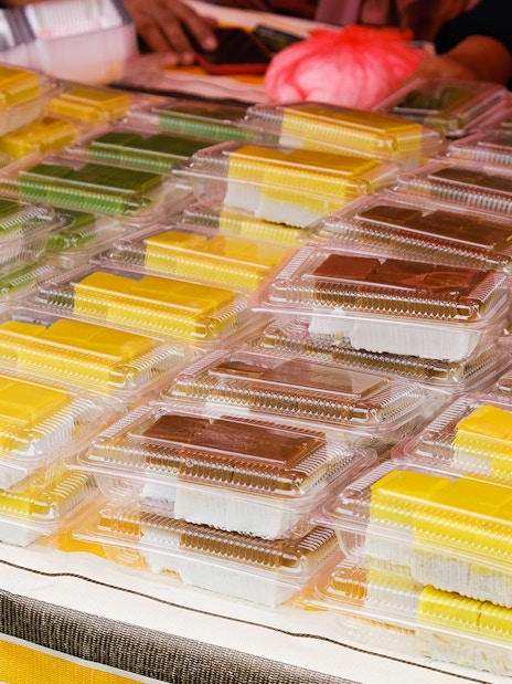 Assorted traditional Indonesian snacks in plastic containers at a Batam market stall.