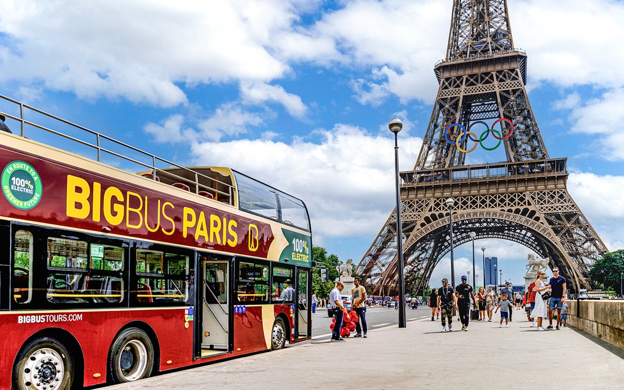 Big Bus Paris tour near Eiffel Tower with Olympic rings, Paris, France.