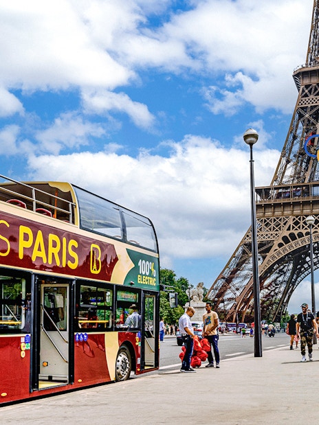 Big Bus Paris tour near Eiffel Tower with Olympic rings, Paris, France.