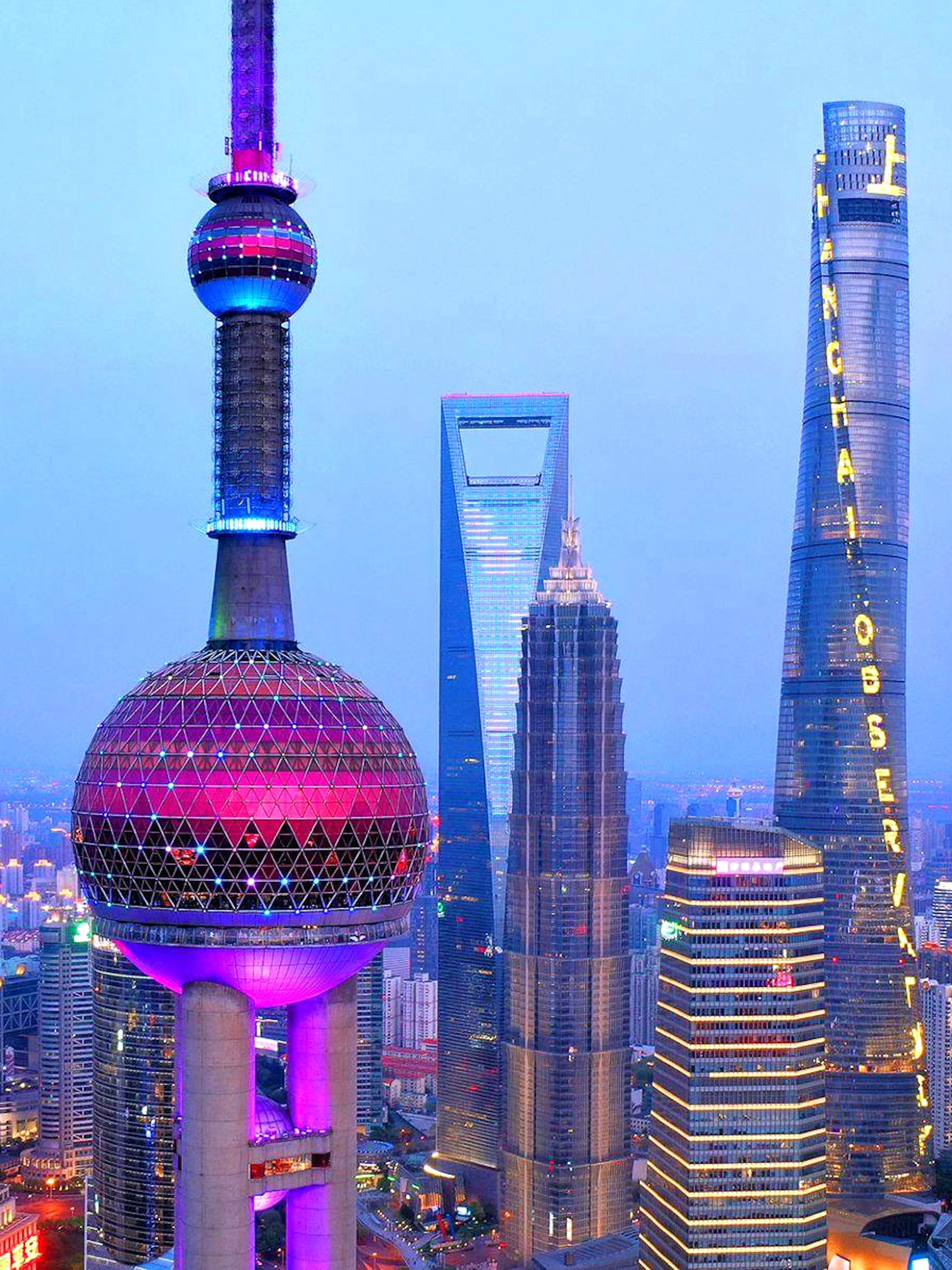 Oriental Pearl Tower and Shanghai skyline at dusk.
