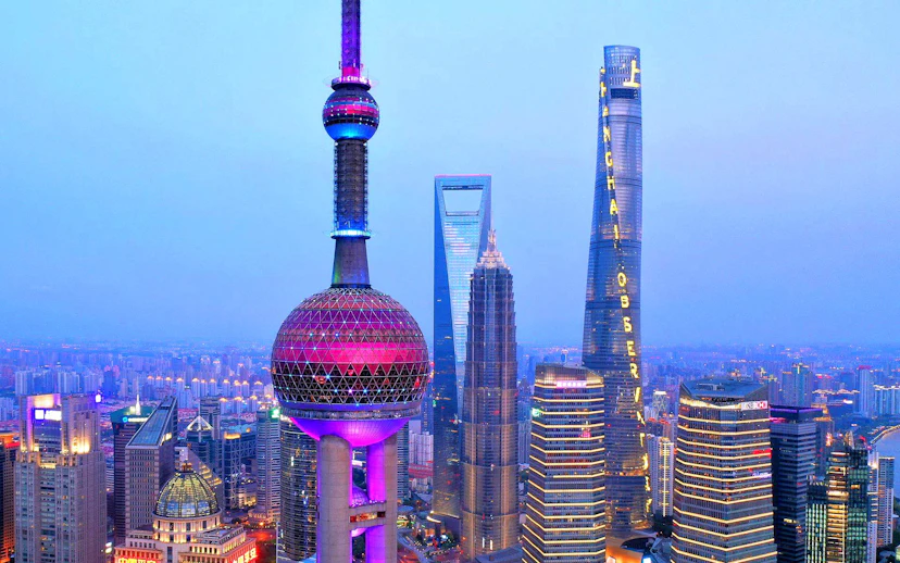 Oriental Pearl Tower and Shanghai skyline at dusk.