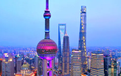 Oriental Pearl Tower and Shanghai skyline at dusk.