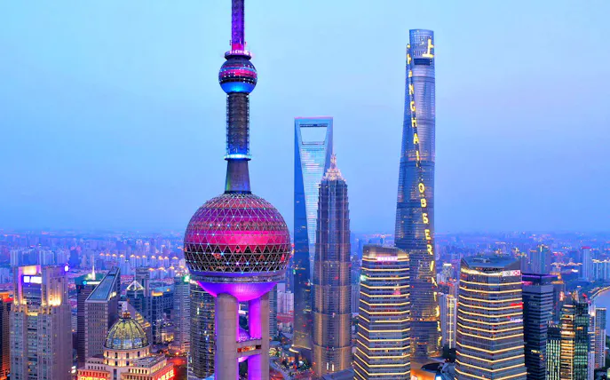 Oriental Pearl Tower and Shanghai skyline at dusk.