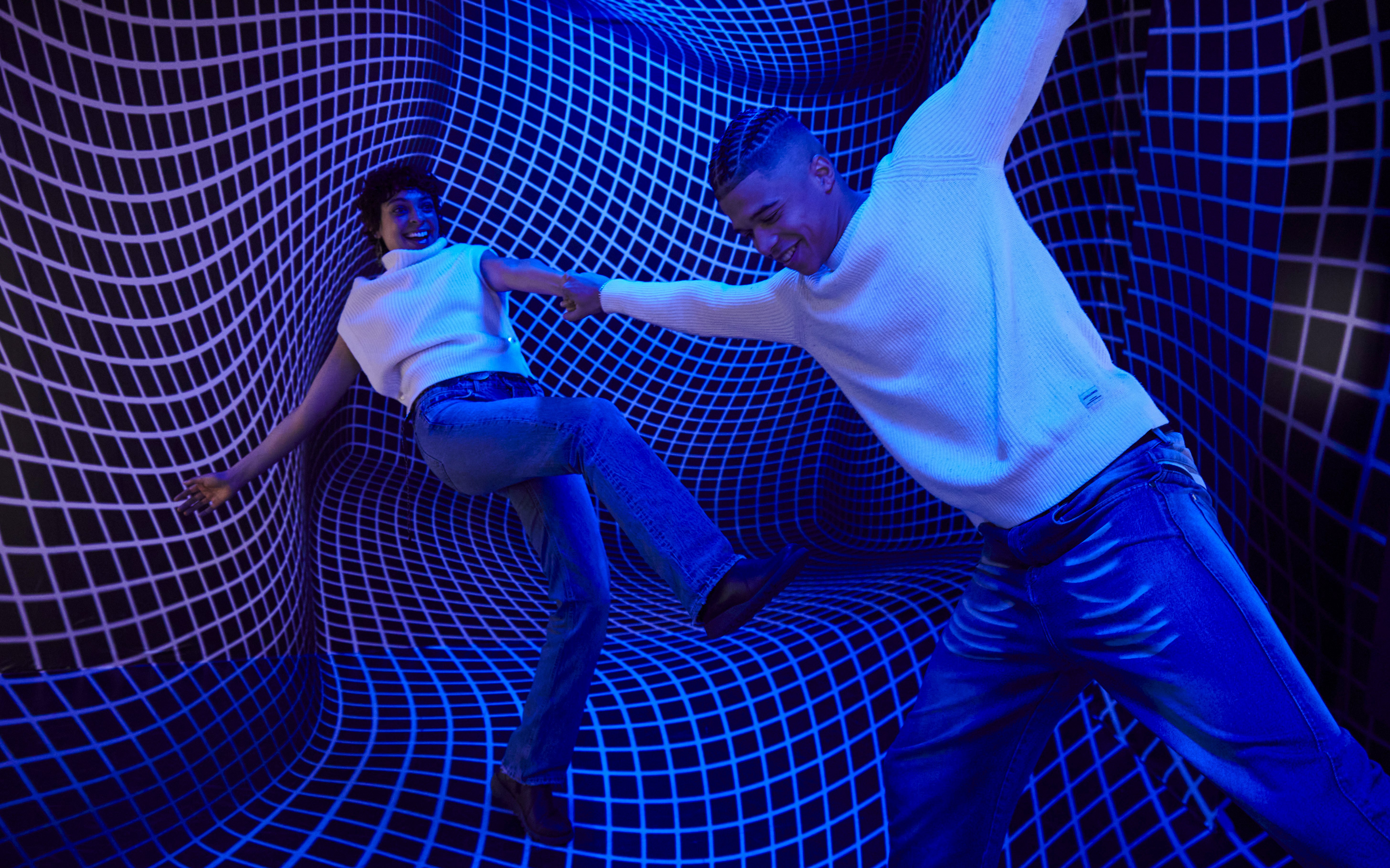 Guests interacting in a blue optical illusion room at the Twist Museum, London.