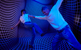 Guests interacting in a blue optical illusion room at the Twist Museum, London.
