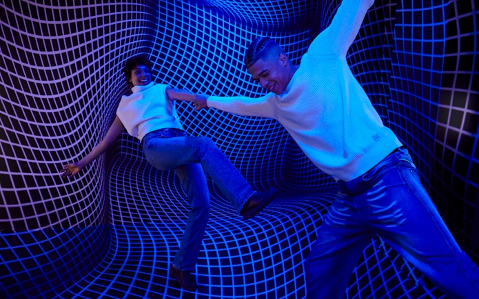 Guests interacting in a blue optical illusion room at the Twist Museum, London.