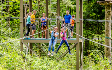 Participants enjoying a zipline at Ropes Park Interlaken amidst lush greenery.