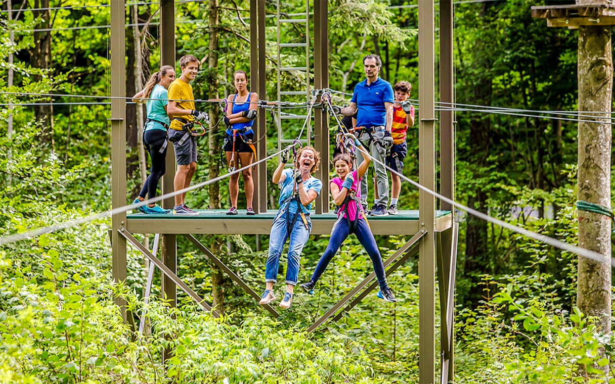 Participants enjoying a zipline at Ropes Park Interlaken amidst lush greenery.