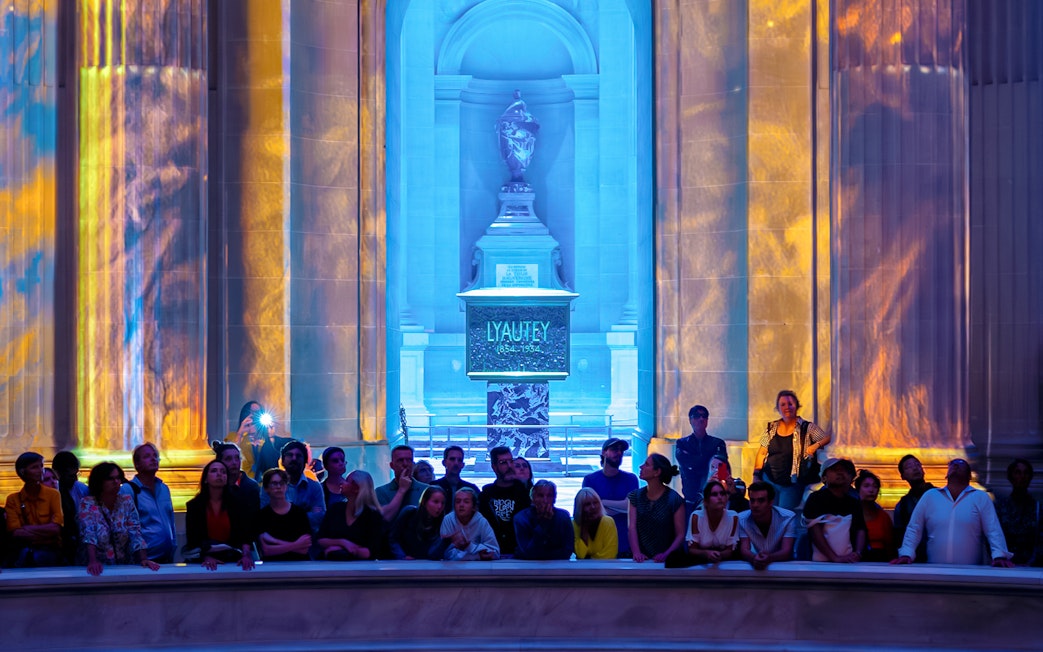 Audience at Aura Immersive show, Invalides stage with colorful light projections.