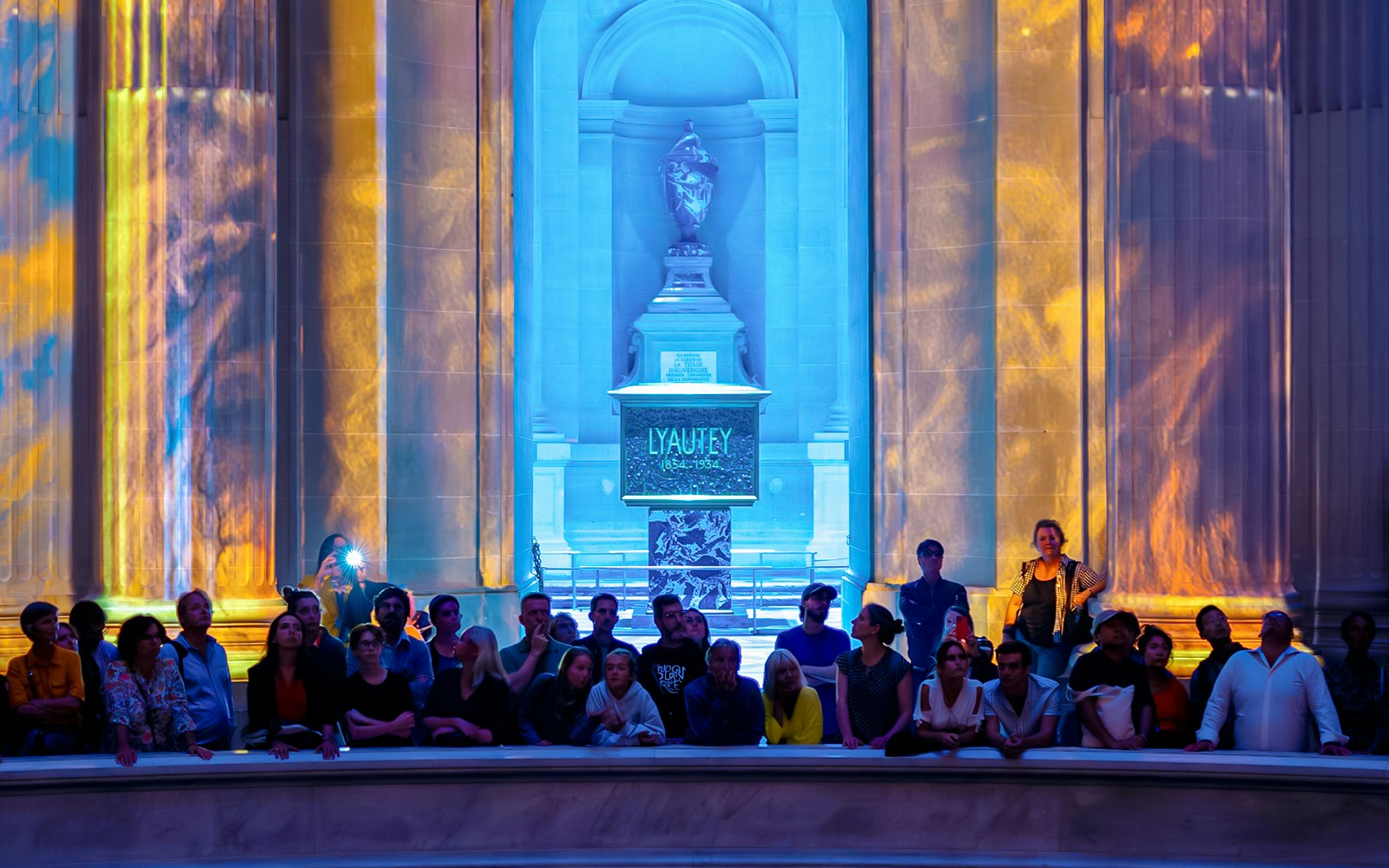 Audience at Aura Immersive show, Invalides stage with colorful light projections.