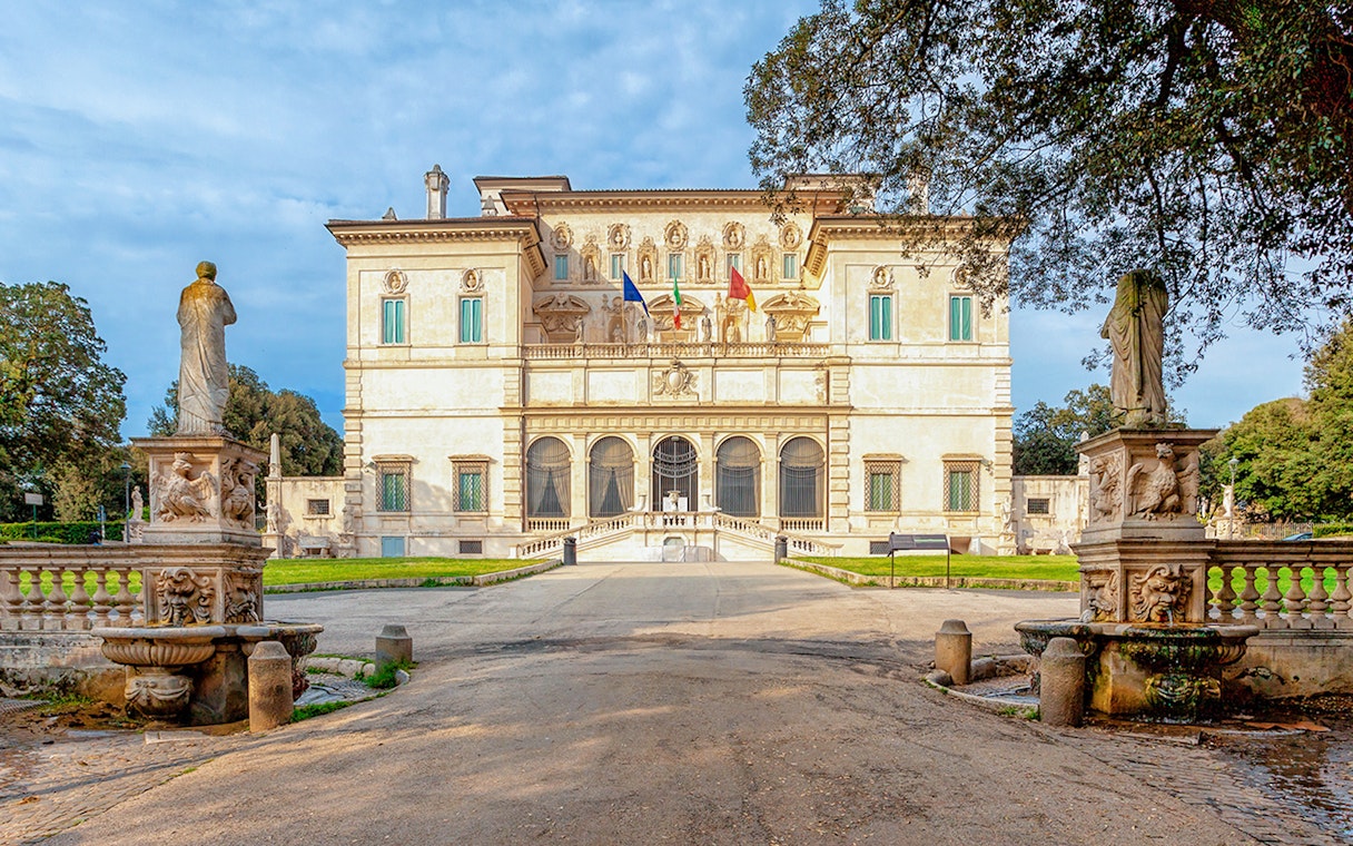 Villa Borghese facade with statues and trees during sunset in Rome, Italy.
