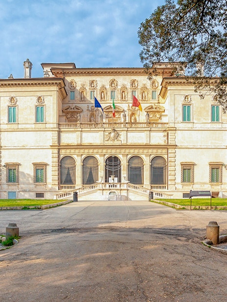 Villa Borghese facade with statues and trees during sunset in Rome, Italy.