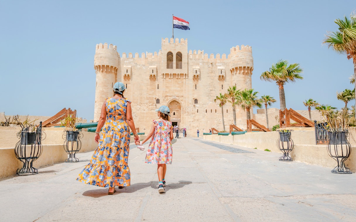 Woman and daughter entering Qaitbay Citadel, Alexandria, exploring historic fortress.