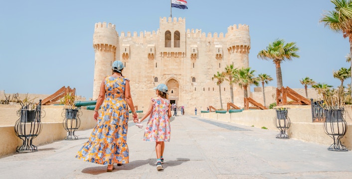 Woman and daughter entering Qaitbay Citadel, Alexandria, exploring historic fortress.
