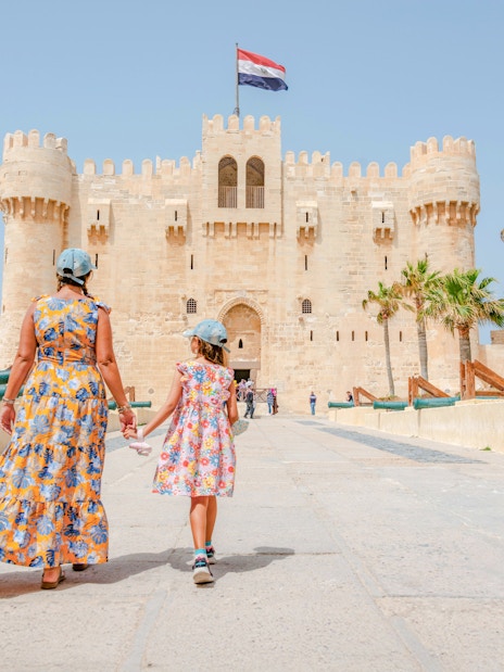 Woman and daughter entering Qaitbay Citadel, Alexandria, exploring historic fortress.