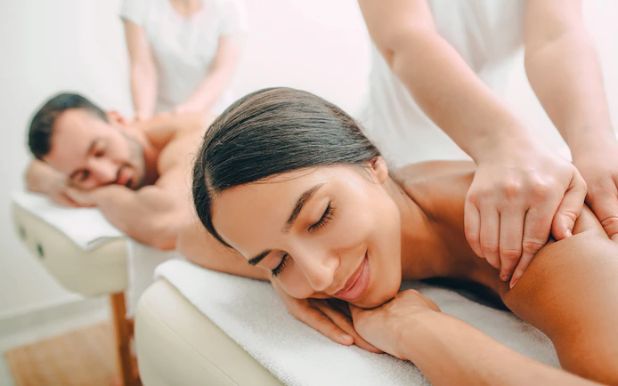Couple receiving back massages at a spa.