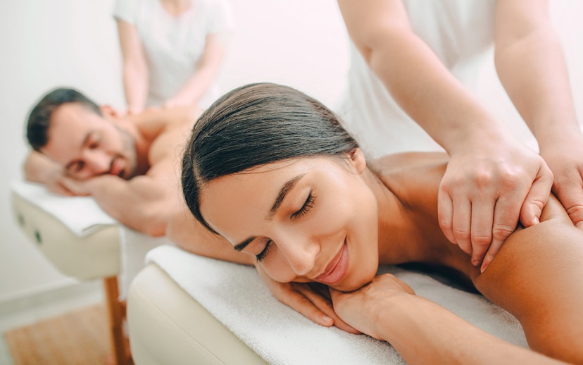 Couple receiving back massages at a spa.