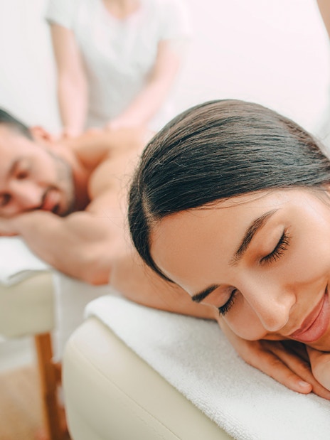 Couple receiving back massages at a spa.