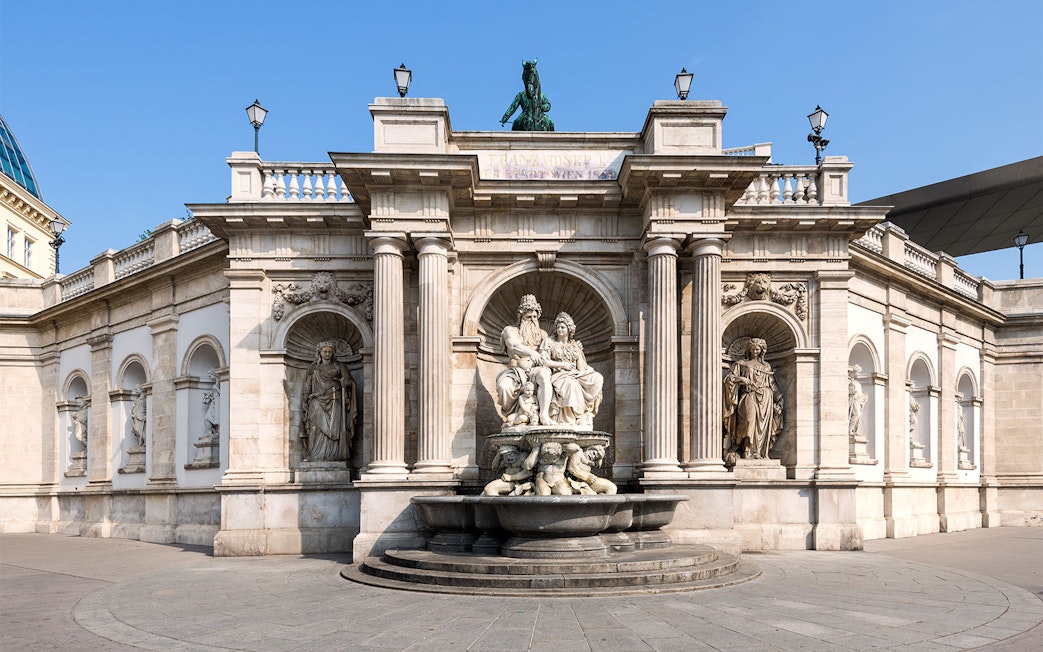 Albertina Museum entrance with ornate statues and fountain in Vienna.