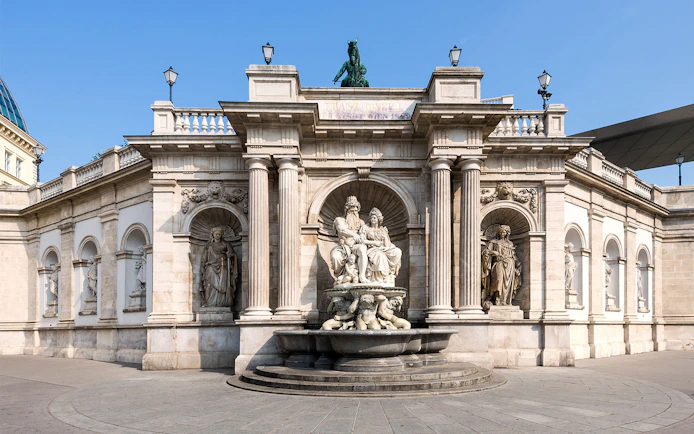 Albertina Museum entrance with ornate statues and fountain in Vienna.