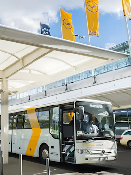Shuttle bus at Munich Airport terminal with Lufthansa flags.