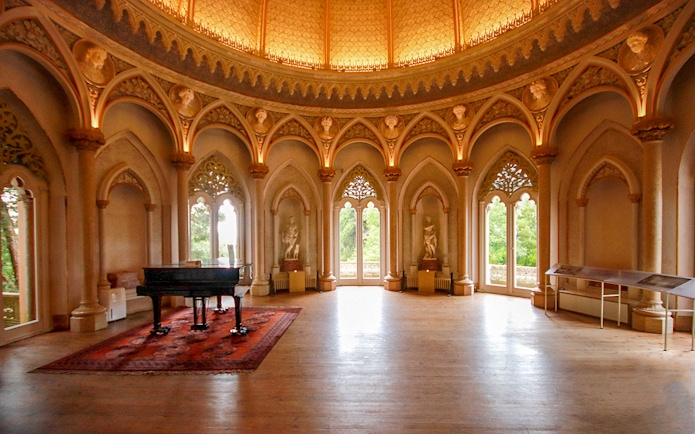 Monserrate Palace interior with grand piano and ornate arches in Sintra, Portugal.