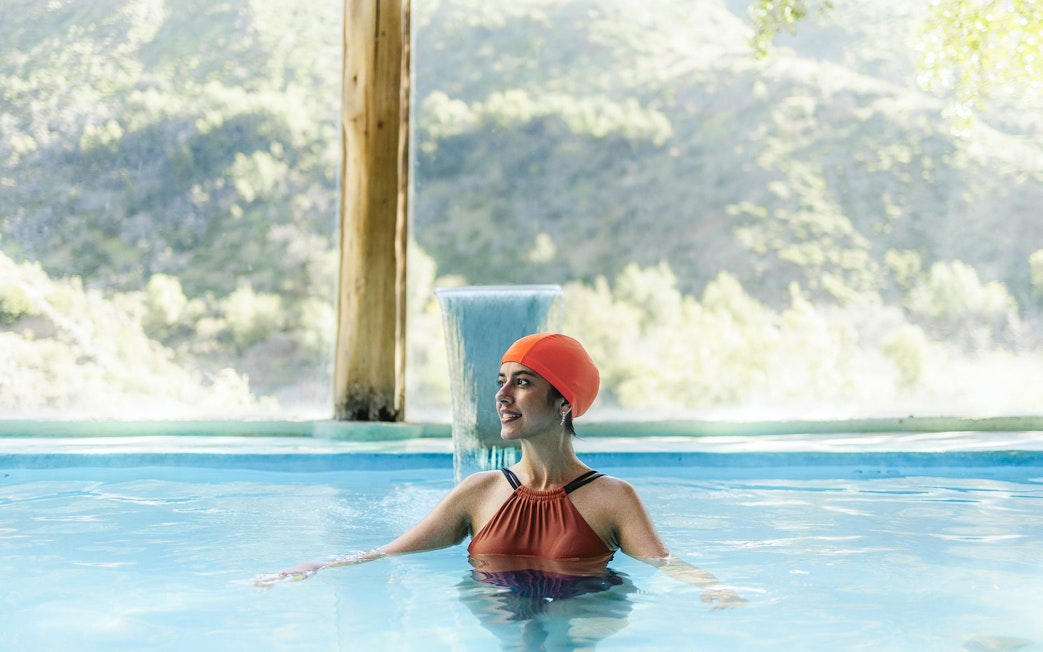 Tourist relaxing in indoor pool at Santuario del Río Spa, Cajón del Maipo, Chile.