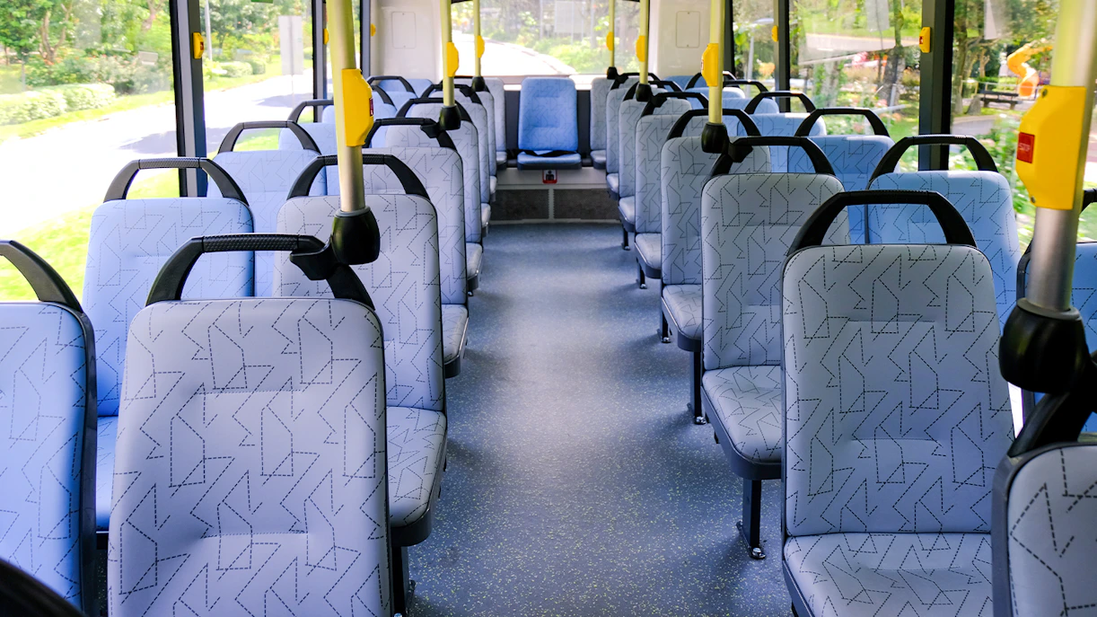 Interior seating of a public bus in Singapore with patterned seats and aisle.