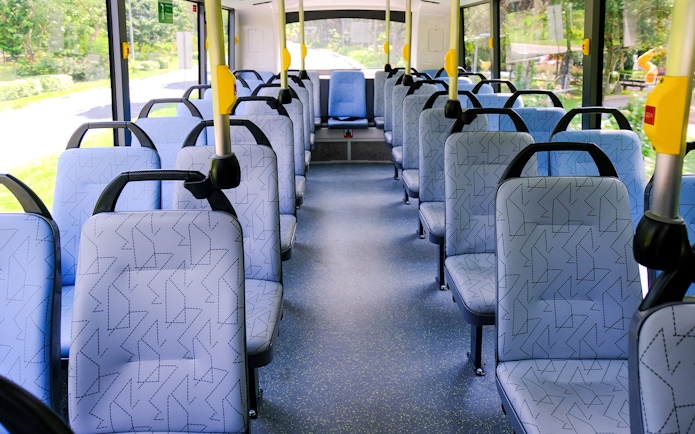 Interior seating of a public bus in Singapore with patterned seats and aisle.