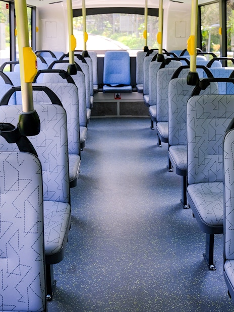 Interior seating of a public bus in Singapore with patterned seats and aisle.