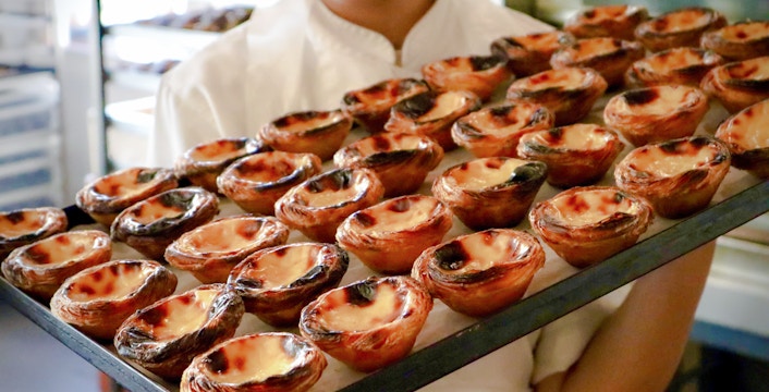 Chef presenting tray of freshly baked Pastel de Nata on Lisbon food tour.