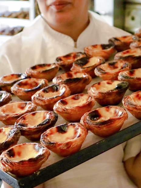 Chef presenting tray of freshly baked Pastel de Nata on Lisbon food tour.