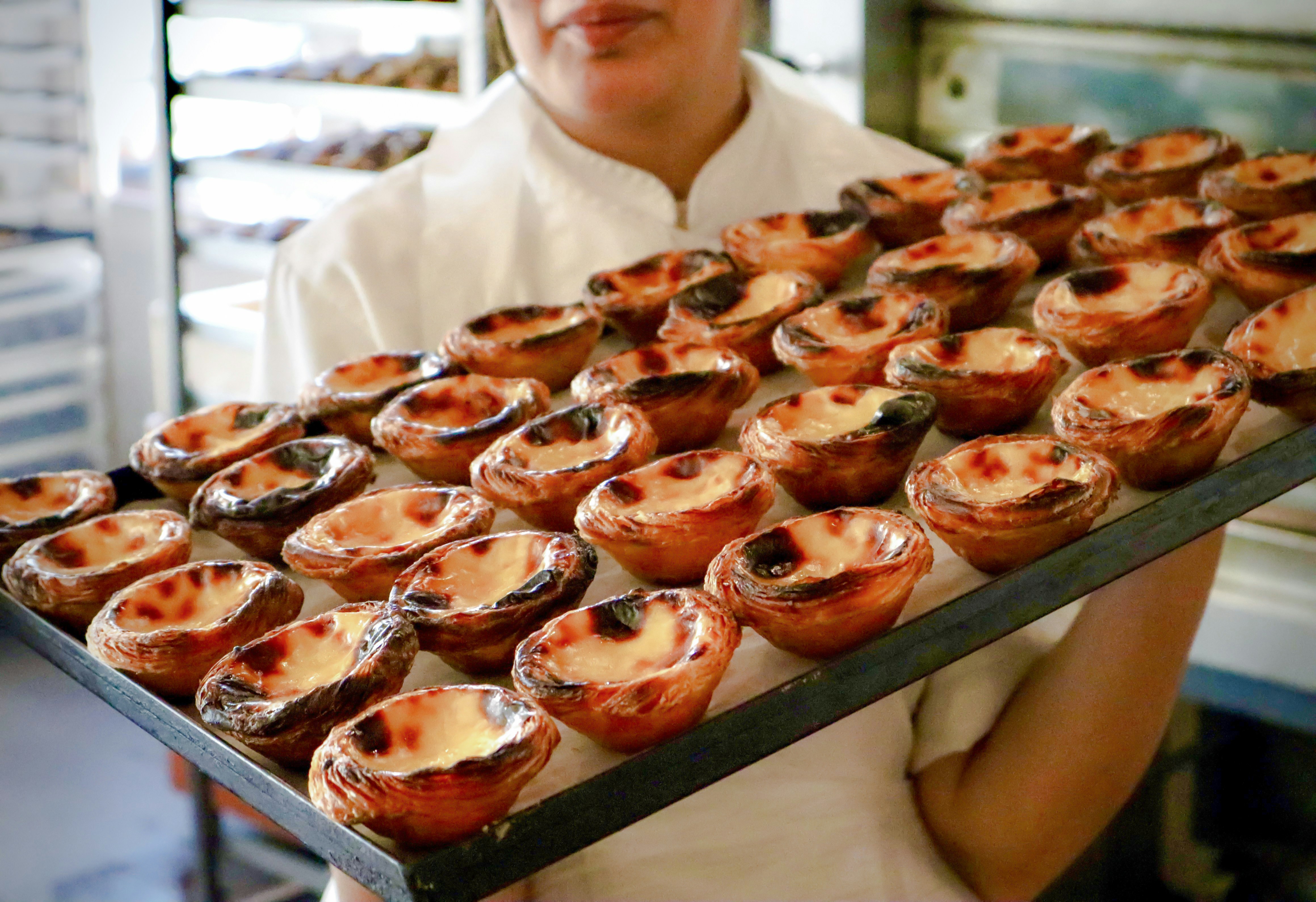 Chef presenting tray of freshly baked Pastel de Nata on Lisbon food tour.