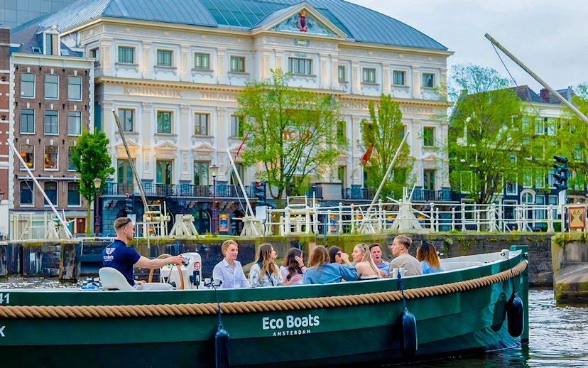 Amsterdam canal cruise with passengers enjoying an evening ride past historic buildings.